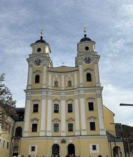 Yellow twin-towered Basilica St. Michael in Mondsee, Austria under a blue sky
