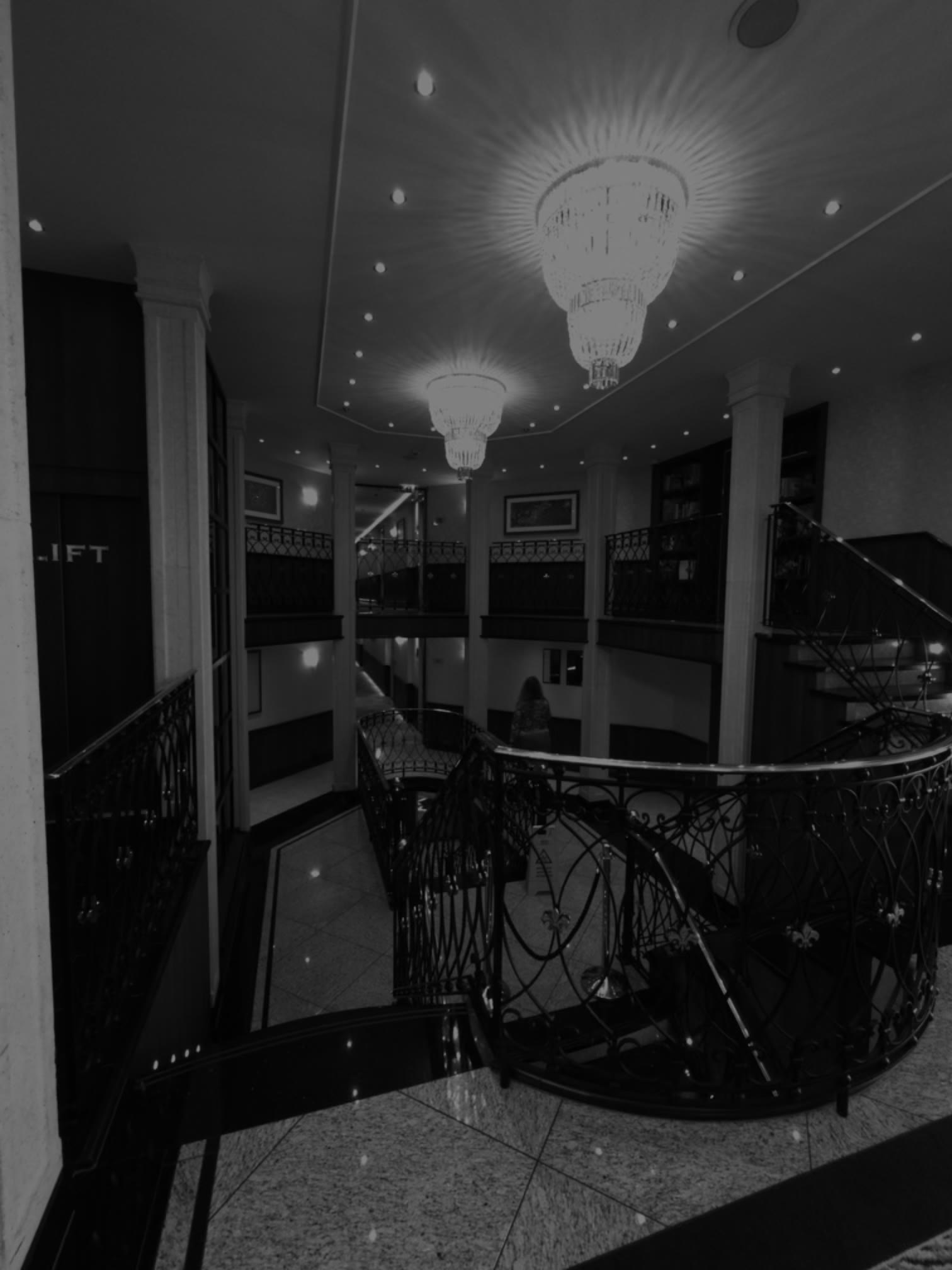 Chandeliers above the curved wrought-iron staircase and open atrium aboard Tauck ms Joy