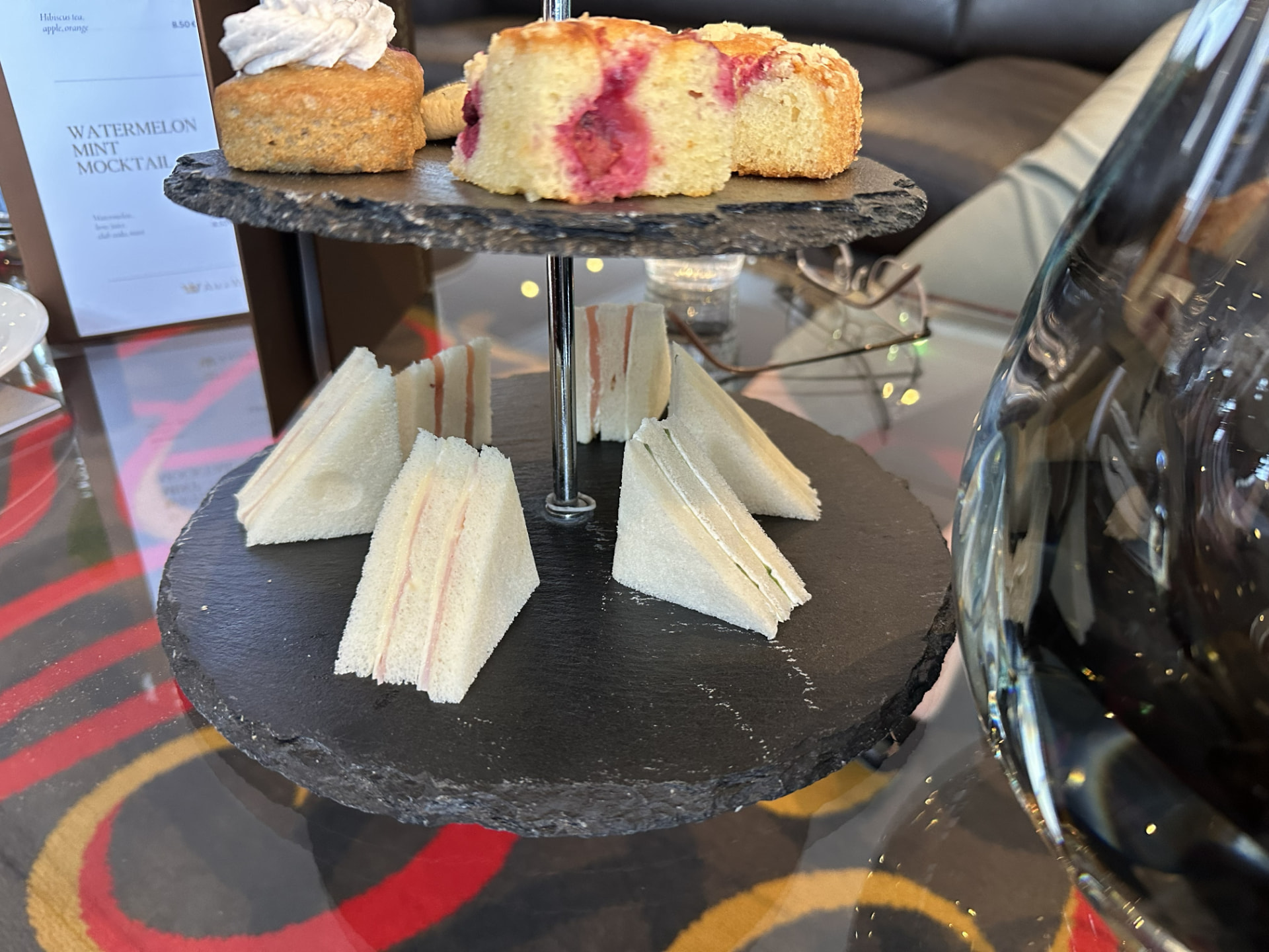 AmaSerena afternoon tea service with finger sandwiches and cakes on a two-tier slate stand