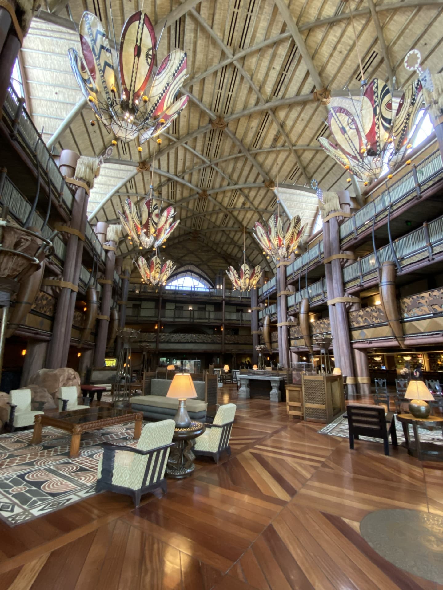 Grand lobby with carved wood columns and colorful hanging lights at Disney's Animal Kingdom Lodge.